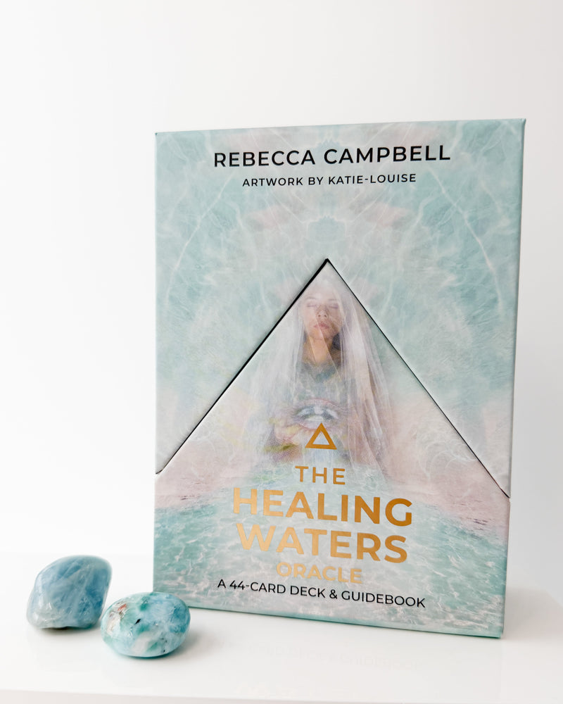 The Healing Waters Oracle card deck and guidebook by Rebecca Campbell on a white background with aquamarine and larimar.