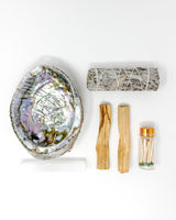 Abalone shell, sage, Palo Santo, and matches on a white background
