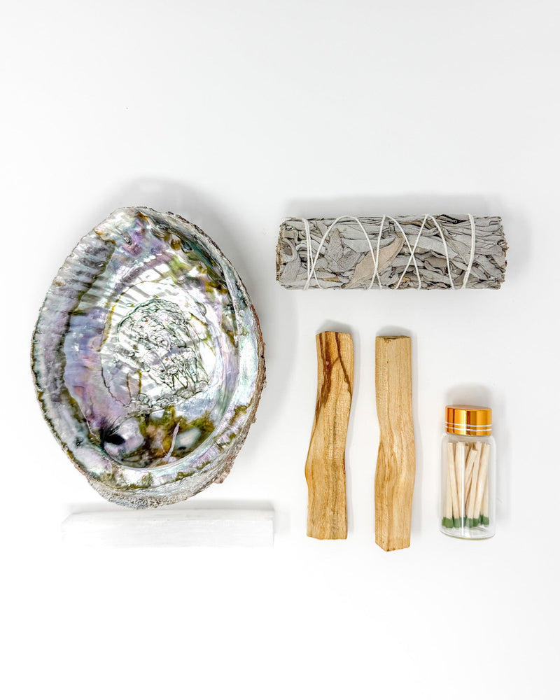 Abalone shell, sage, Palo Santo, and matches on a white background