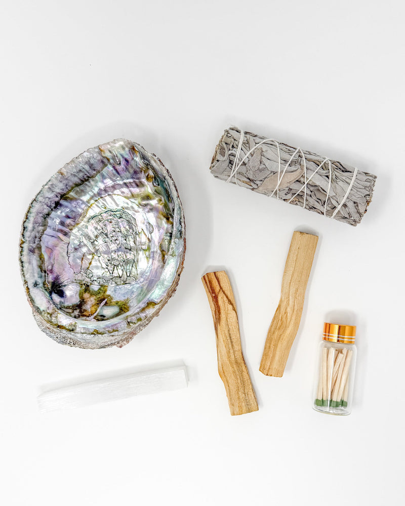 Abalone shell, matches, and wooden tools on a white background